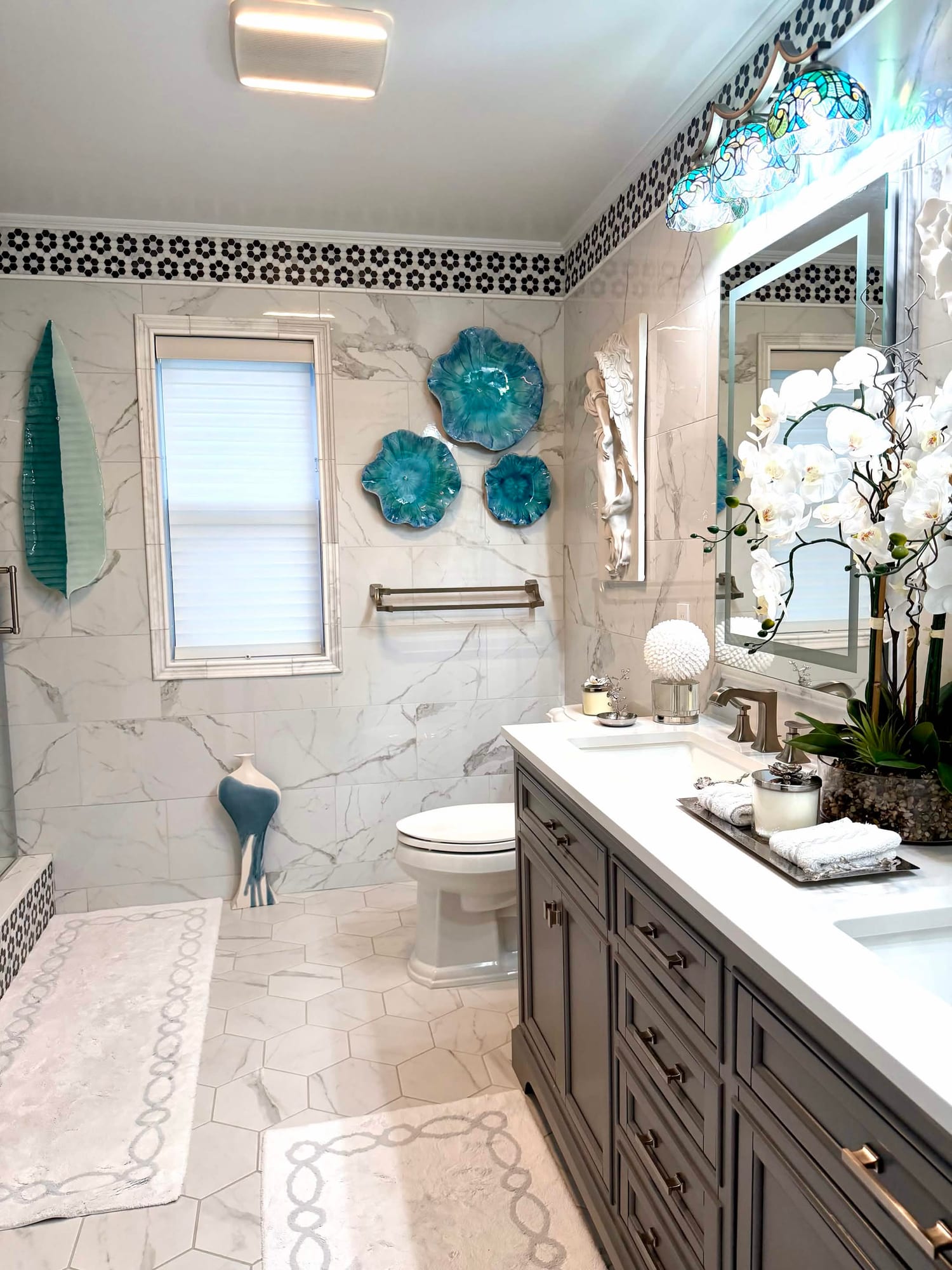 Marble primary bathroom with gray double vanity, quartz tops and a hexagon tile floor