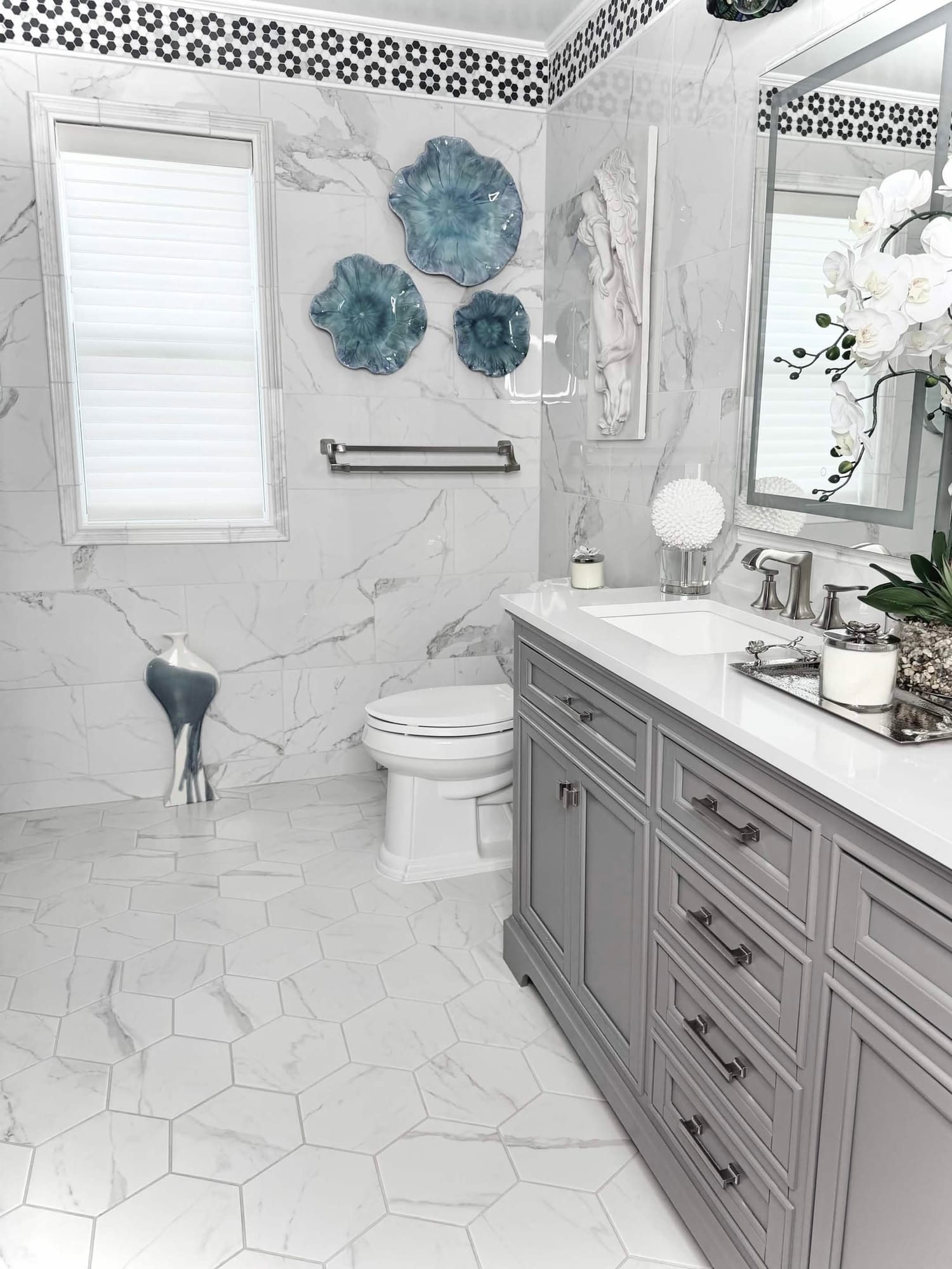 Full bathroom remodel with marble look tile, gray double vanity and hexagon marble floor