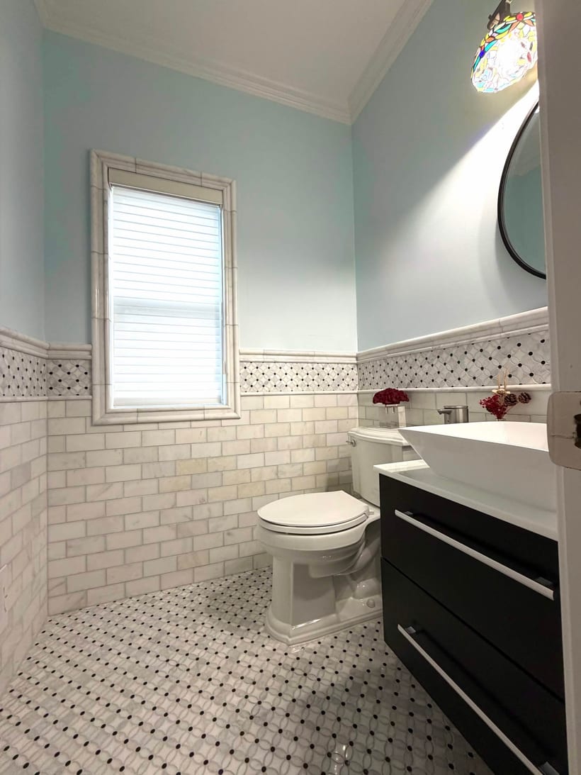 Powder room with blue walls, marble subway tile, penny mosaic floor and a black floating vanity