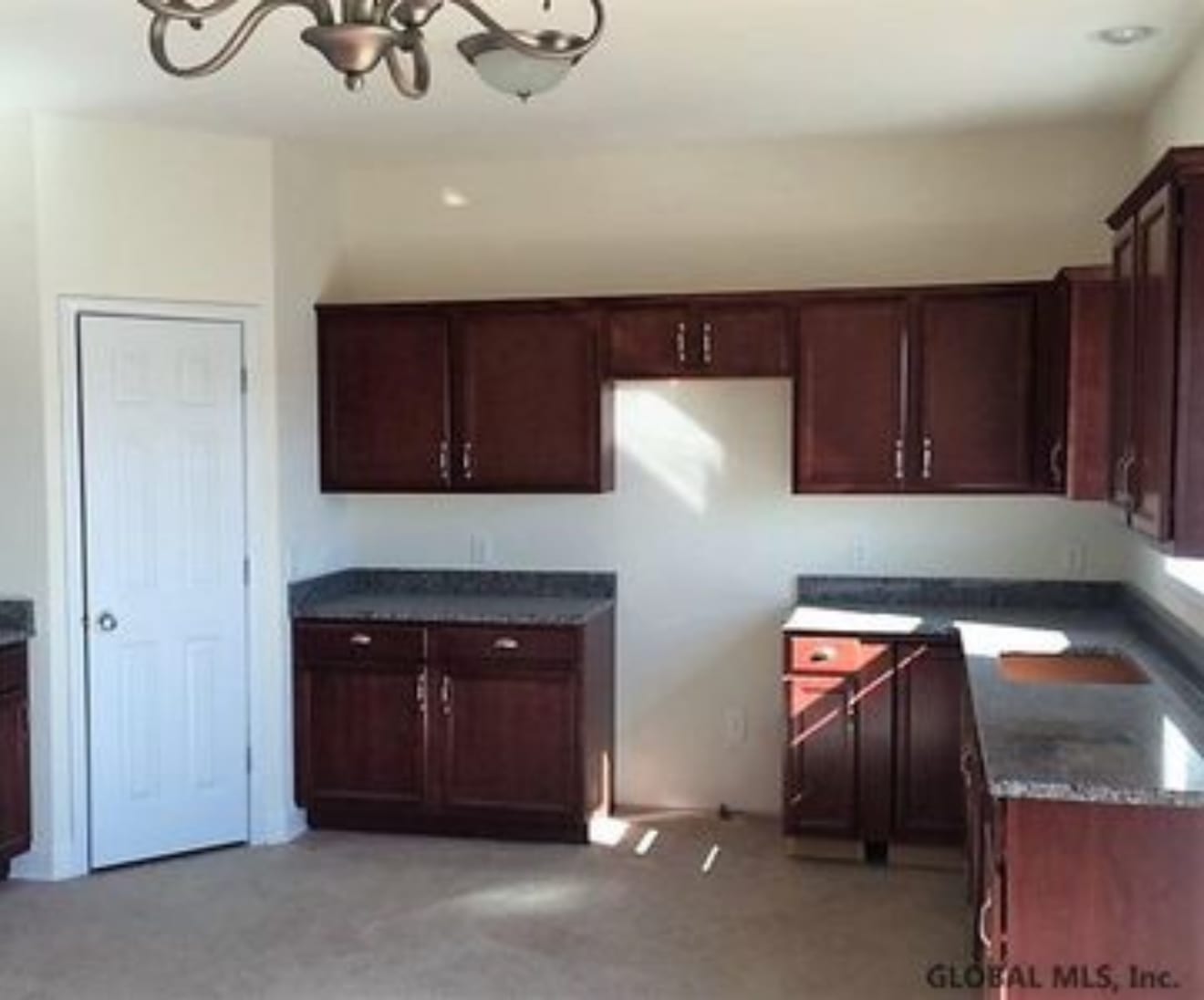 The same kitchen before renovation, with dated cabinets, laminate counters and carpet