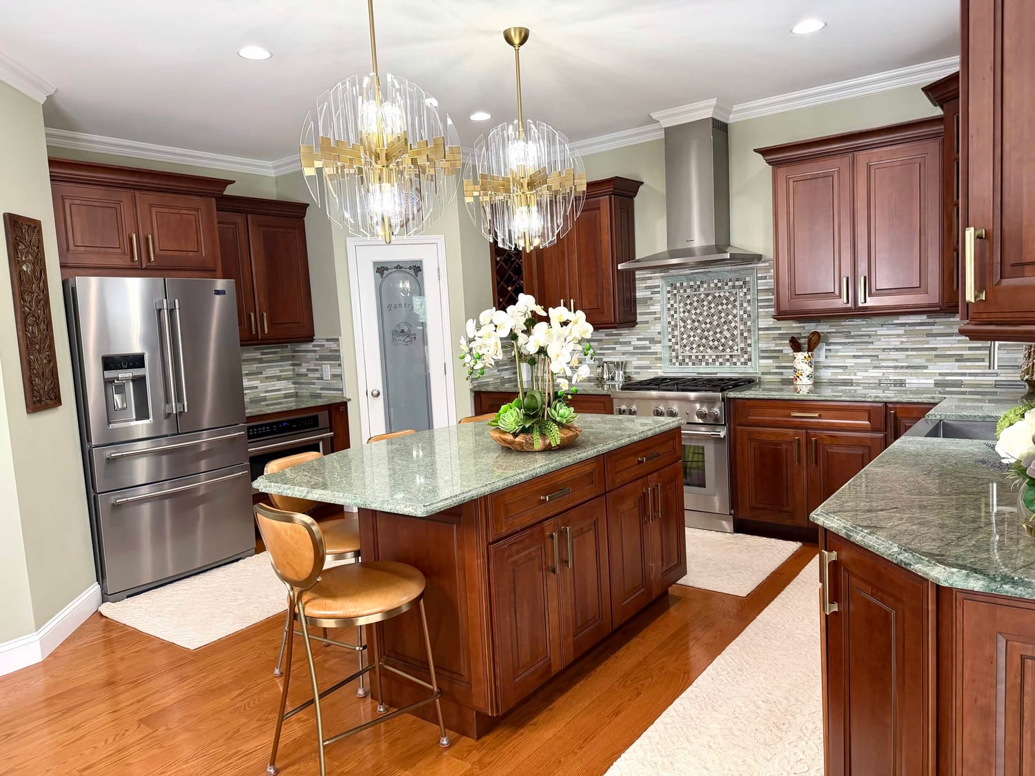 Finished cherry kitchen with a green granite island, stainless appliances and a mosaic tile backsplash