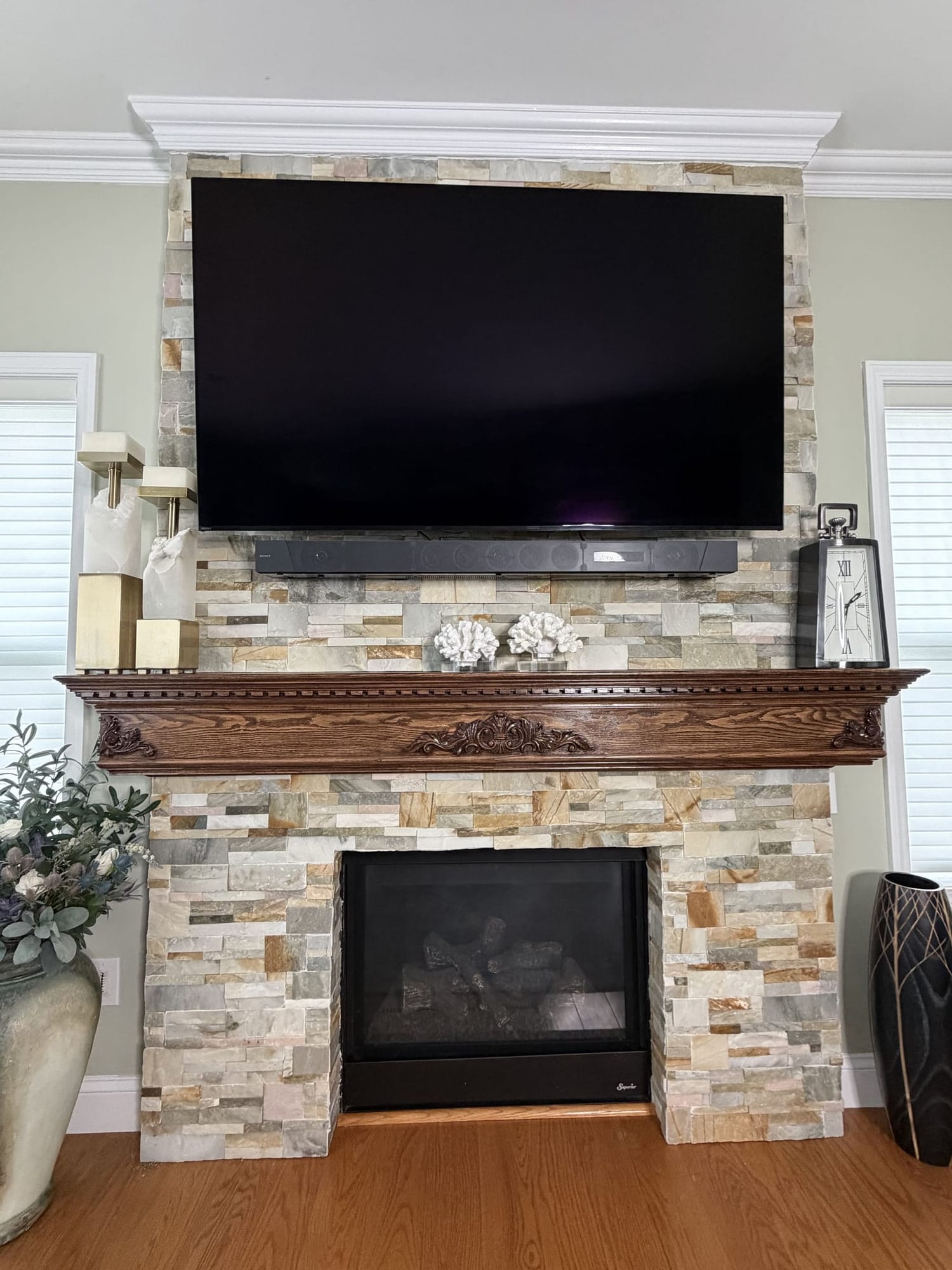 Floor to ceiling stacked stone fireplace with a custom stained wood mantel