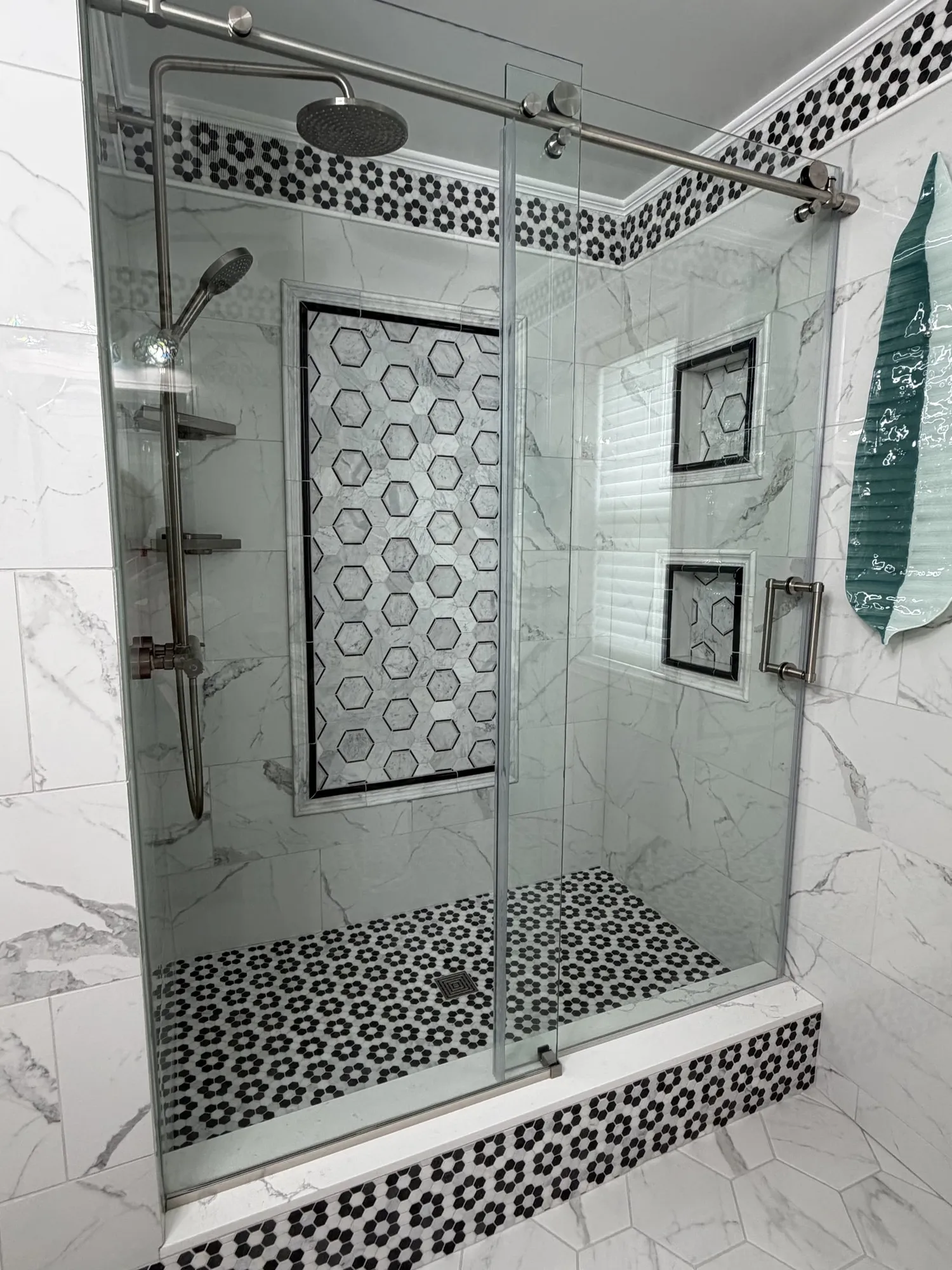Custom frameless glass tile shower with marble walls and hexagon mosaic detail